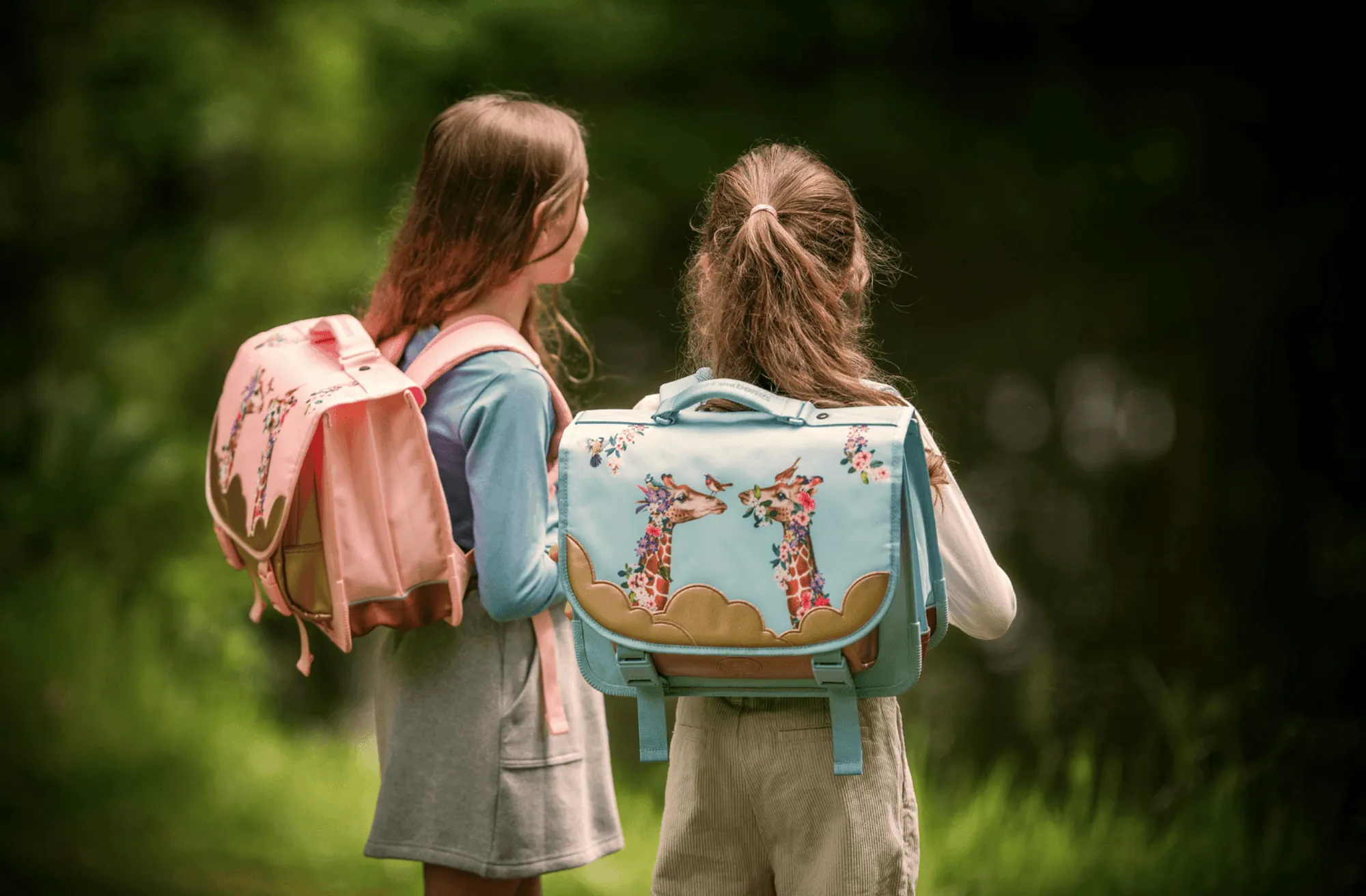 Two girls walking together, satchels on their backs.